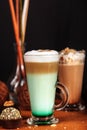 Coffee latte macchiato with mint syrup and whipped cream, in high transparent glasses with cakes, on a dark background Royalty Free Stock Photo