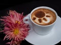 Coffee latte sun shaped froth art design next to pink flowers Royalty Free Stock Photo