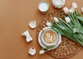 Coffee latte with white tulips , candles on brow background.