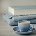 Coffee in a light blue cup and book in blue binding with a knitted scarf on a wooden background. Royalty Free Stock Photo