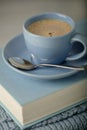 Coffee in a light blue cup and book in blue binding with a knitted scarf on a wooden background. Royalty Free Stock Photo