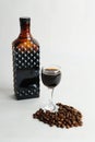 Coffee liqueur in dark glass bottle and poured into a glass. White background, scattered coffee beans Royalty Free Stock Photo