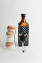 Coffee liqueur in dark glass bottle and filled shot glass. Macarons cookies french dessert. White background, isolated Royalty Free Stock Photo