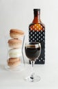 Coffee liqueur in dark glass bottle and filled shot glass. Macarons cookies french dessert. White background, isolated Royalty Free Stock Photo