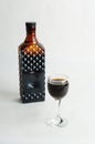 Coffee liqueur in dark glass bottle and filled shot glass. White background, isolated Royalty Free Stock Photo