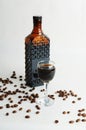Coffee liquor in dark glass bottle and poured into a glass. White background, scattered coffee beans Royalty Free Stock Photo