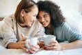 Coffee, love and lesbian couple on bed in conversation for bonding and relaxing together. Happy, rest and interracial Royalty Free Stock Photo