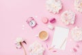 Coffee, macaroons, alarm clock, office supply, peony flowers and empty notebook.Fashion woman working desk. Flat lay