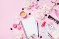 Coffee, macaroons, alarm clock, office supply, peony flowers and notebook on pink pastel table top view. Flat lay style.