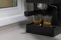 Coffee machine producing coffee in two glass cups on a kitchen table