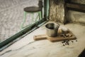 Coffee metal cup and roasted coffee beans with a small cheese cake on vintage and rustic kitchen board in a small restaurant in Royalty Free Stock Photo