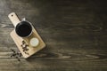 Coffee metal cup and roasted coffee beans with a small cheese cake on vintage and rustic kitchen board in a small restaurant in Royalty Free Stock Photo