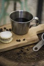 Coffee metal cup and roasted coffee beans with a small cheese cake on vintage and rustic kitchen board in a small restaurant in Royalty Free Stock Photo