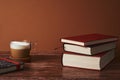 Coffee with milk and books on a brown wooden table.