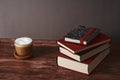 Coffee with milk and books on a brown wooden table.