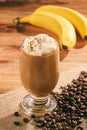 Coffee milk cocktail with banana on wooden background