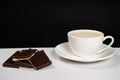 Coffee with milk cream, cappuccino in a saucer cup and chocolate on a black background Royalty Free Stock Photo