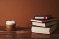 Coffee with milk and books on a brown wooden table.