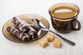 Coffee with milk, marshmallow in chocolate on saucer, spoon, sugar