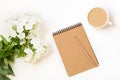 Coffee with milk, phlox flower, scretch-book on white table from above. Female working and creative desk. Mockup. Flat lay.