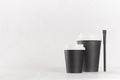 Coffee mockup - big and small black paper cups with white caps and sugar bag on white wood table with copy space, coffee shop. Royalty Free Stock Photo