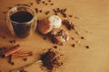 Coffee moody image. Glass cup with fresh coffee and roasted beans,ground coffee on spoon, macarons, chocolate, cinnamon on brown