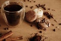 Coffee moody image. Glass cup with fresh coffee and roasted beans,ground coffee on spoon, macarons, chocolate, cinnamon on brown Royalty Free Stock Photo