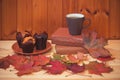 Coffee, muffins, autumn maple leaves and stack of books. Selective focus