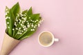 Coffee mug with bouquet of flowers lily of the valley pink pastel background, beautiful breakfast, vintage romantic card, top view Royalty Free Stock Photo