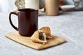 a coffee mug and a croissant broken in half on a cutting board