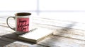 Coffee mug displaying Happy Valentine's Day. sticky note, sitting with an open notebook on a white wooden table Royalty Free Stock Photo