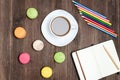 Coffee mug, macaroons, colored pencils and a notebook on a wooden background Royalty Free Stock Photo