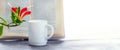 Coffee mug near an open book and a flowerpot in front of the window, panorama, copy space