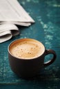 Coffee mug with newspaper on teal rustic table, cozy breakfast
