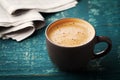 Coffee mug with newspaper on teal rustic table, cozy breakfast