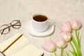 Coffee mug, a notebook with pen and pink tulips on the table Royalty Free Stock Photo