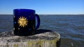 Coffee mug on post beside sea