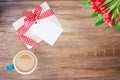 Coffee mug, present box with blank paper tag and tulips on rustic wooden table. Top view. Breakfast on Valentine, Mother or Womens