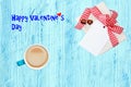 Coffee mug, present box with chocolate hearts and blank paper tag on blue wooden desk with Valentine text. Breakfast on Valentine Royalty Free Stock Photo