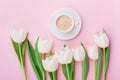 Coffee mug with spring tulip flowers for good morning on pink table above in flat lay style. Breakfast on Mothers or Womens day.