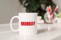 Coffee mug with text MONDAY in workplace background