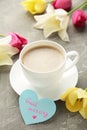 Coffee mug with tulip flowers and notes good morning on grey background, breakfast on Mothers day or Womens day. Vertical photo Royalty Free Stock Photo