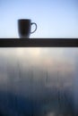 Coffee mug on window sill with water condensation due to air temperature differences