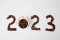 Coffee New Year 2023 concept. Number made of coffee beans. A cup filled with coffee beans as a Christmas ball. On white Royalty Free Stock Photo