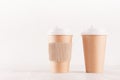 Coffee packing mockup - two craft brown paper cups with white cap, kraft cup holder on white wood board with copy space. Royalty Free Stock Photo