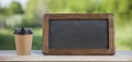 Coffee paper cup with chalk board, on wood table, summer day background Royalty Free Stock Photo