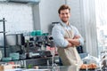 Coffee Passion. Young barista at coffee shop leaning back on counter crossed arms smiling confident