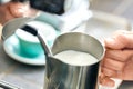 Coffee Passion. Young barista at coffee shop steaming milk in pitcher close-up Royalty Free Stock Photo