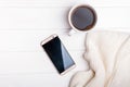 Coffee, phone and knitted sweater on the white table