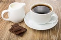 Coffee, pieces of chocolate and milk jug on table